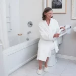 An elderly woman uses a PT Rail to transfer from the toilet.