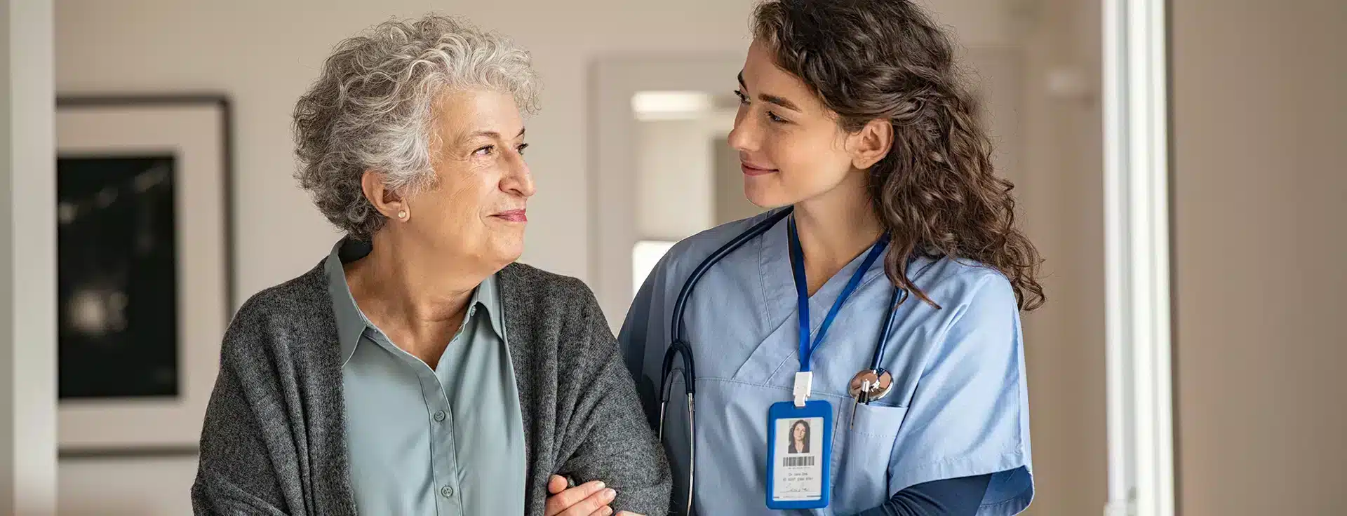 Occupational therapist helping a senior woman walking by holding her arm.